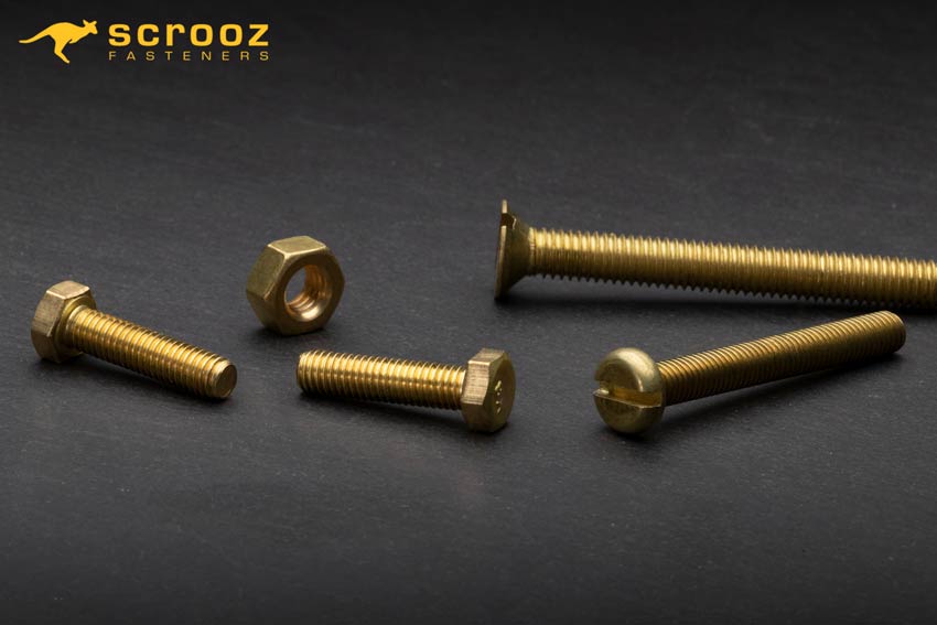 Brass Bolts, Brass Nuts, Brass Washers, Brass Machine Screws on metal background splash image by Scrooz Fasteners